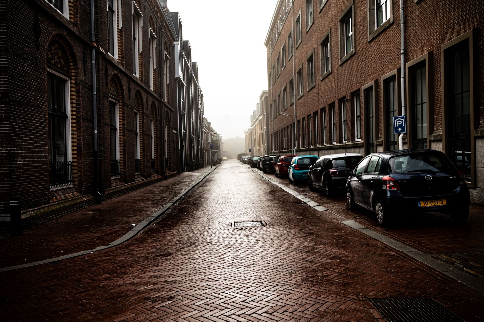 Black executive car on a wet brick-lined Manchester street