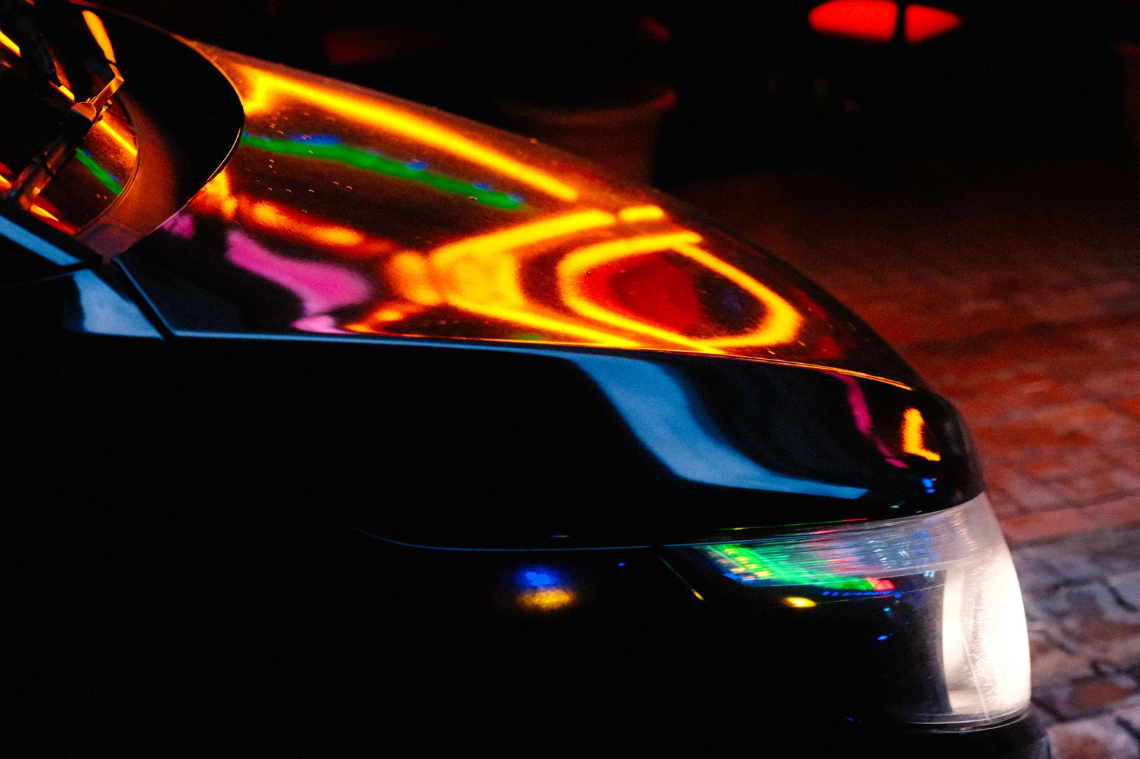 Black car on a neon-lit Nashville street at night