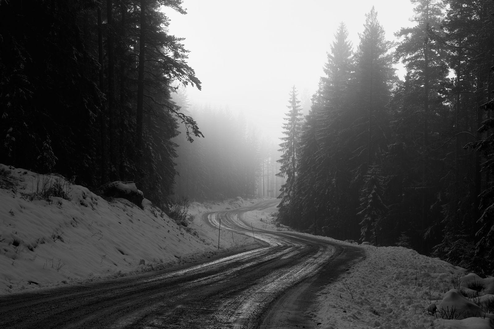 Black car on a snowy Norwegian road in winter light