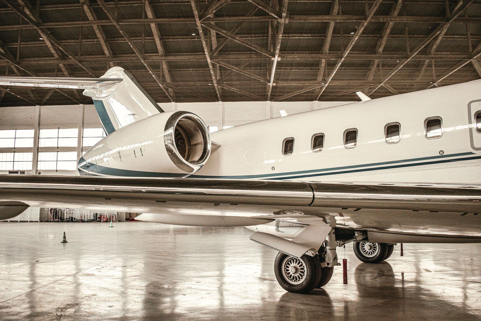 Business jet in a lit hangar at an FBO in the evening