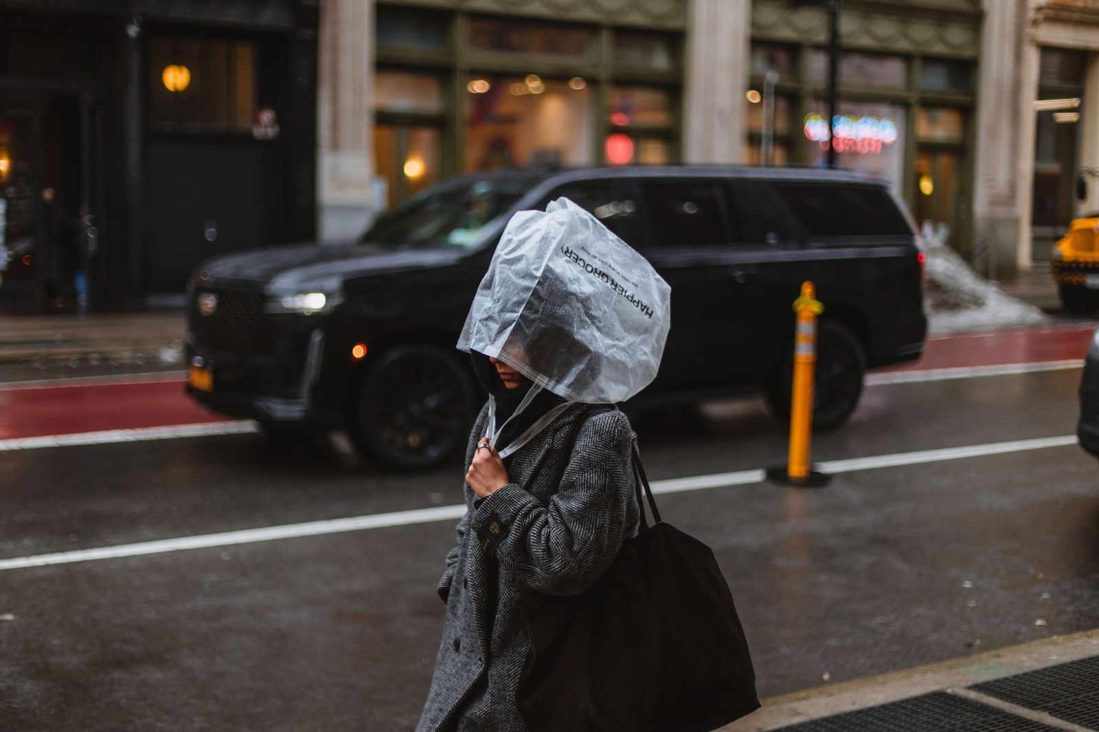 A black executive SUV on a downtown street at night in the rain