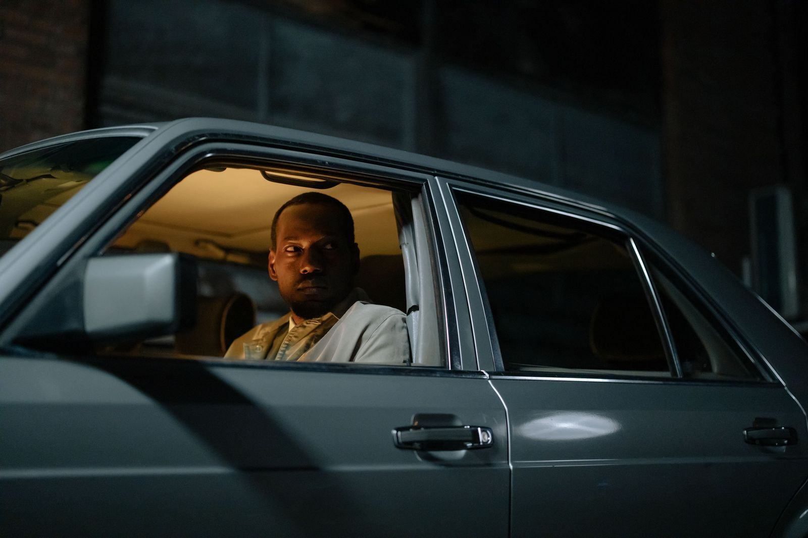 A security-trained driver holding the rear door of an armoured SUV at night