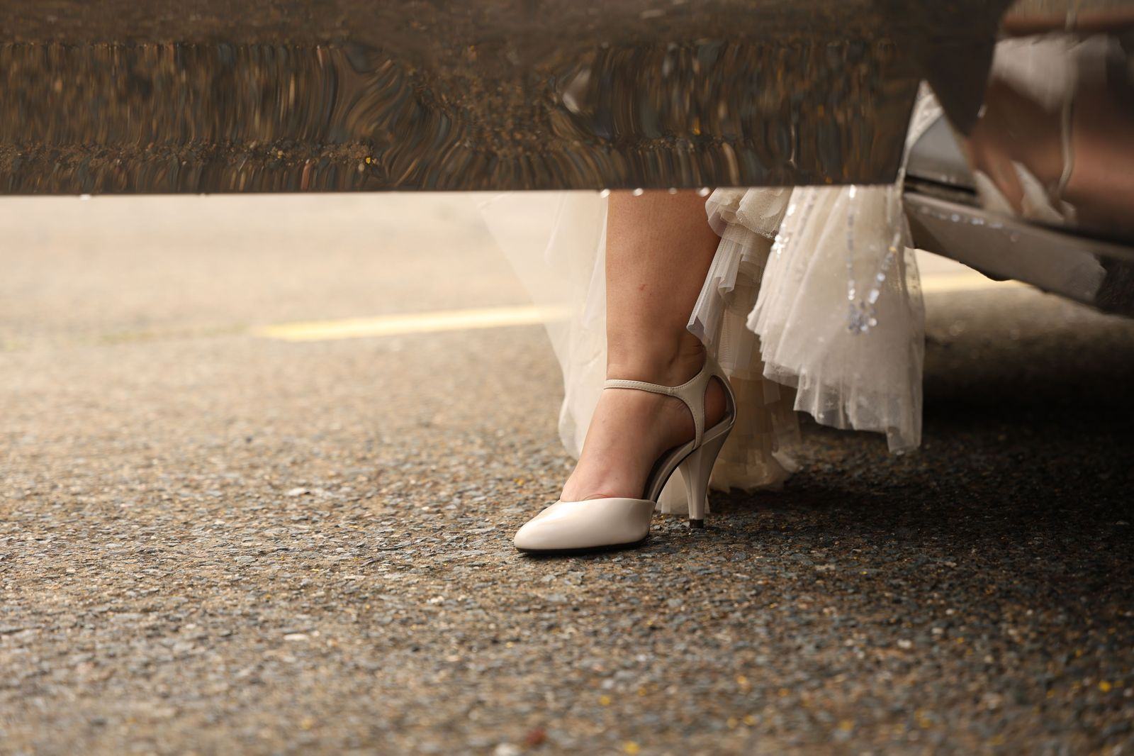 A bride stepping out of a chauffeur-driven wedding car at the ceremony